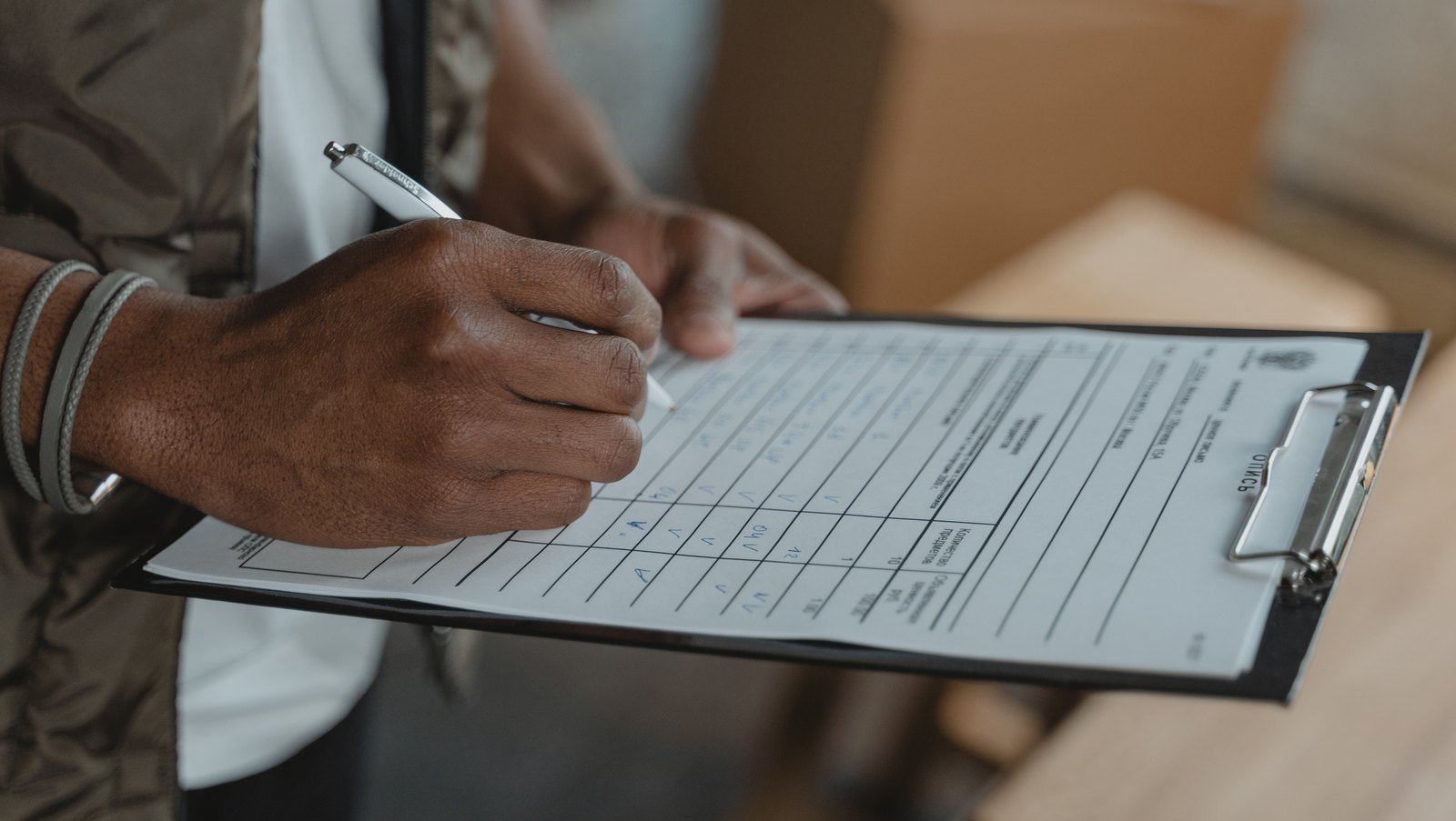 A humanitarian worker recording information on a clipboard during a field review.